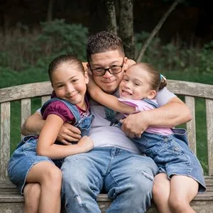 Father hugging 2 young daughters