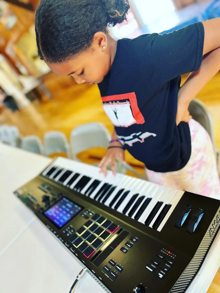 Child playing a keyboard at Fine Feather Foundation's program
