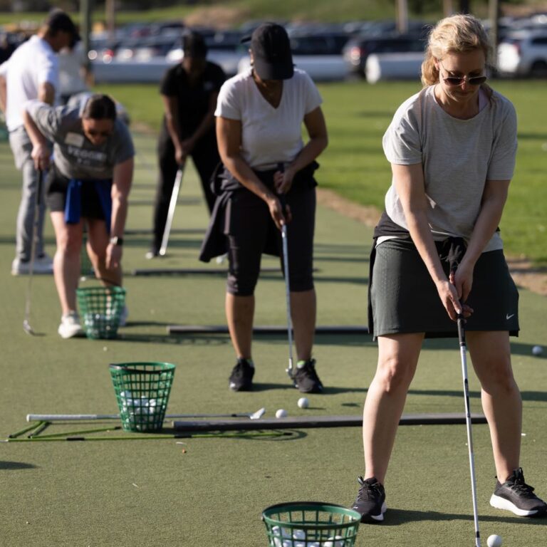 Women United Golf event attendees swinging golf clubs