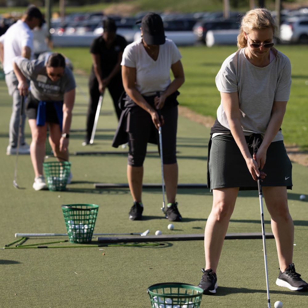 Women United Golf event attendees swinging golf clubs